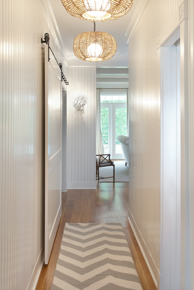 Cette image montre un couloir marin avec un mur blanc et un sol en bois brun.