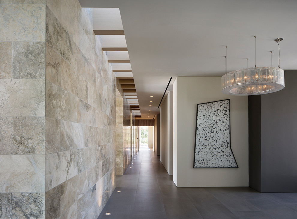 Aménagement d'un grand couloir contemporain avec un sol en carrelage de porcelaine, un sol gris et un mur beige.