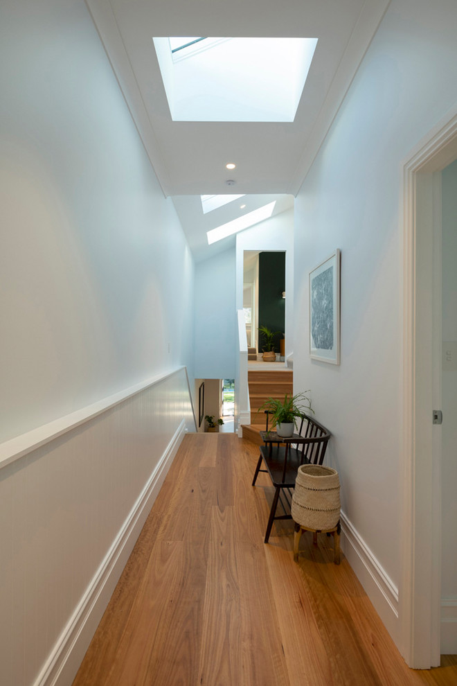 Foto di un piccolo ingresso o corridoio design con pareti bianche, pavimento in legno massello medio e pavimento marrone