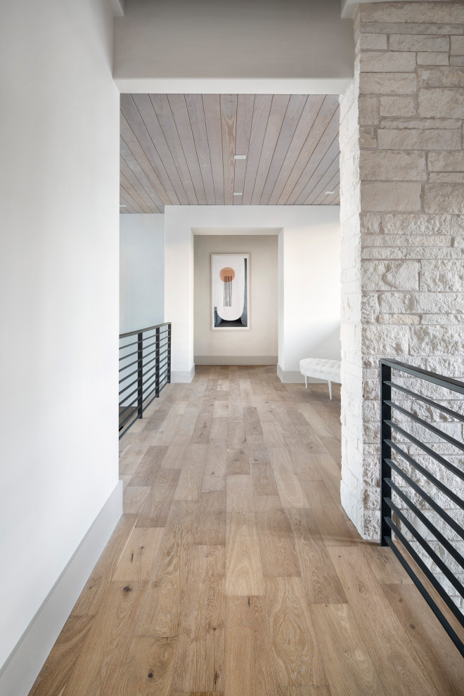 Cette photo montre un grand couloir moderne avec un mur blanc, un sol en bois brun, un sol marron, un plafond en bois et un mur en parement de brique.