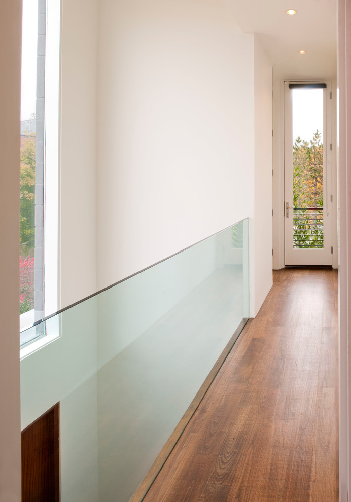 Inspiration pour un couloir minimaliste avec un mur blanc et un sol en bois brun.