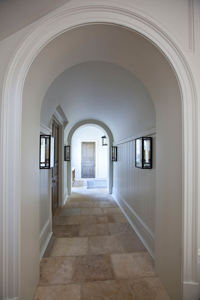 Klassisk inredning av en mellanstor hall, med vita väggar, travertin golv och beiget golv