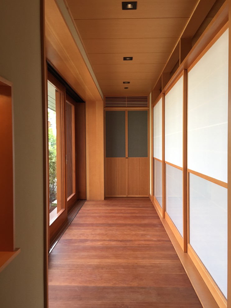 Hallway - mid-sized zen medium tone wood floor hallway idea in Orange County with white walls