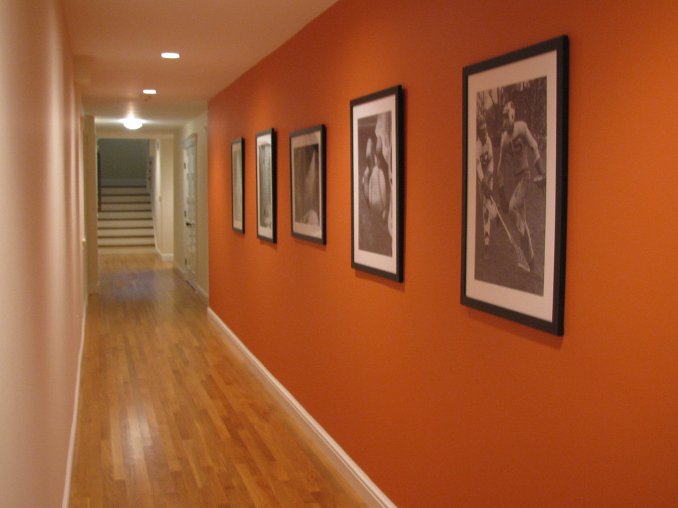 Large eclectic medium tone wood floor and brown floor hallway photo in Boston with orange walls