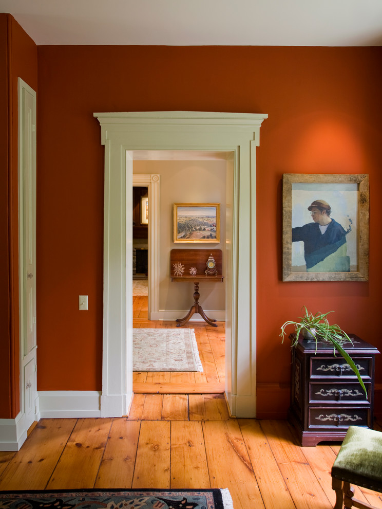 Ejemplo de recibidores y pasillos clásicos con paredes rojas, suelo de madera en tonos medios y suelo naranja