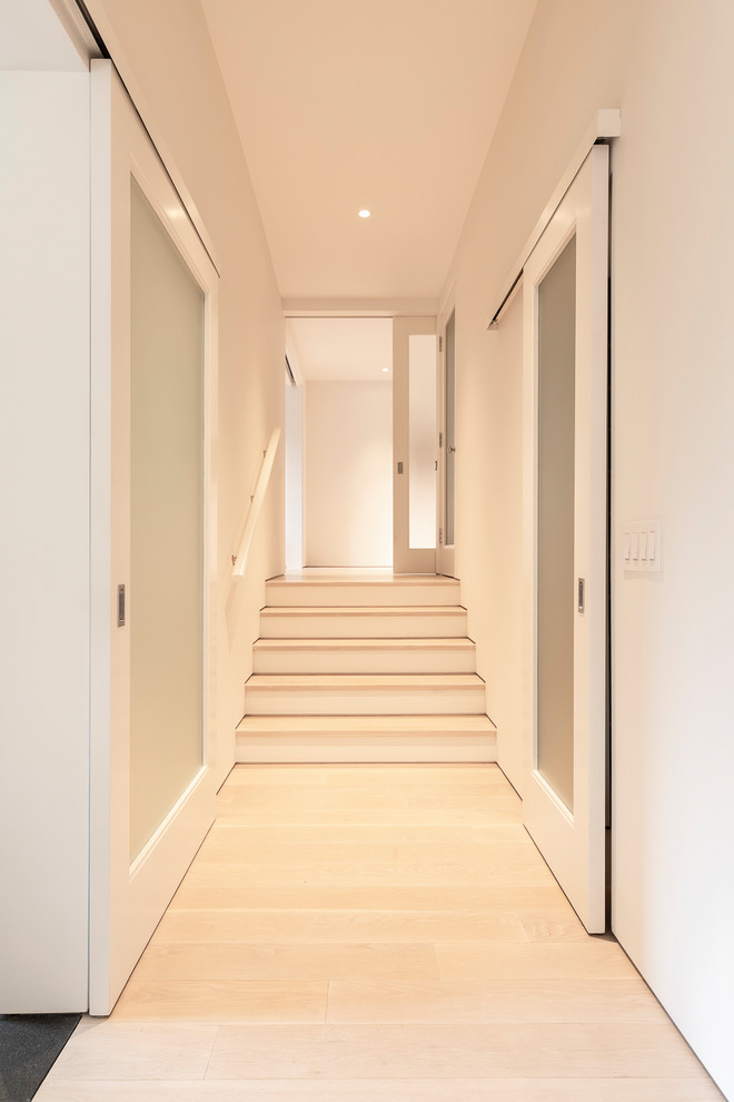 Стильный дизайн: большой коридор в современном стиле с белыми стенами, светлым паркетным полом и белым полом - последний тренд