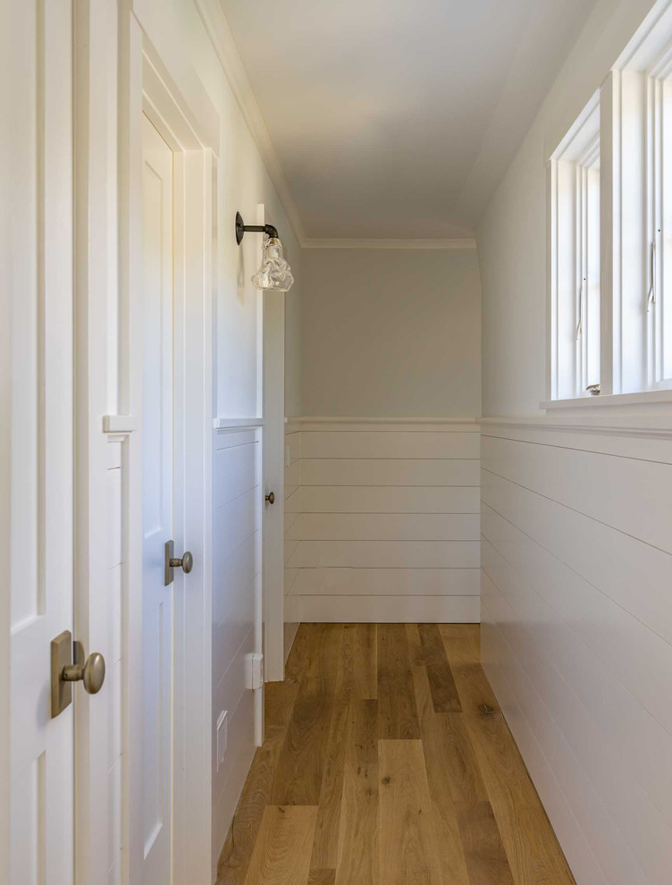 Immagine di un ingresso o corridoio stile marinaro di medie dimensioni con pareti bianche, parquet chiaro e pavimento marrone