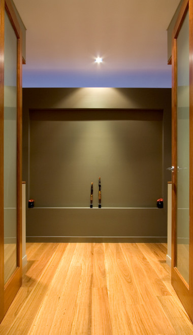 Réalisation d'un grand couloir design avec un mur gris, parquet clair et un sol marron.