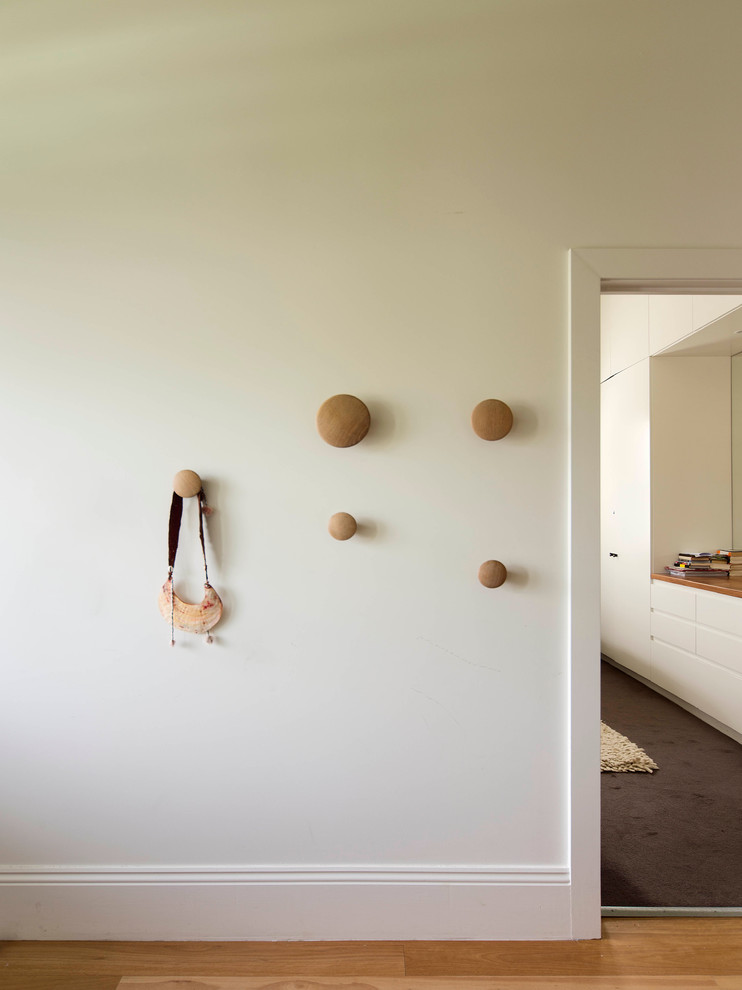 Idée de décoration pour un couloir design de taille moyenne avec un mur blanc et un sol en bois brun.