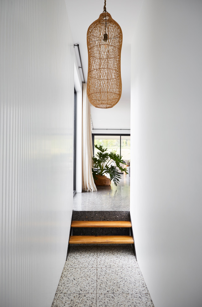Стильный дизайн: большой коридор в современном стиле с белыми стенами, бетонным полом, черным полом и панелями на части стены - последний тренд
