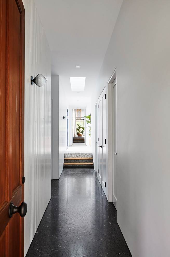 Example of a large minimalist concrete floor and black floor hallway design in Other with white walls