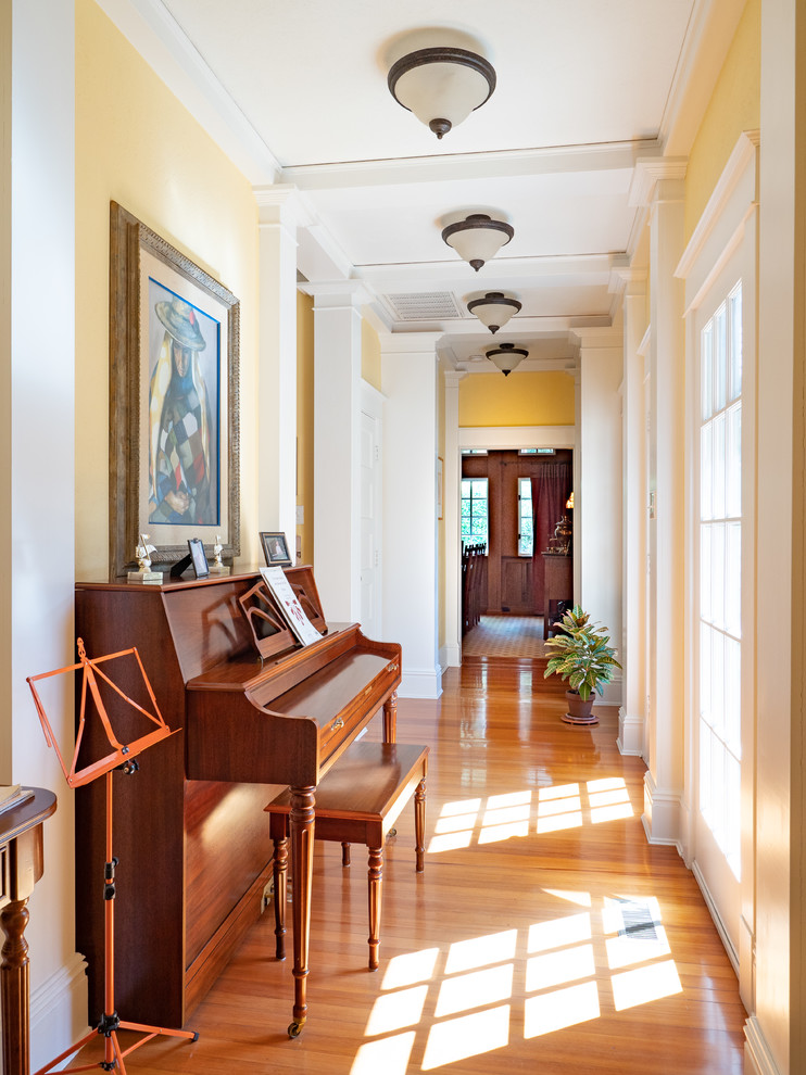 Imagen de recibidores y pasillos de estilo americano con paredes amarillas, suelo de madera en tonos medios, suelo marrón y iluminación