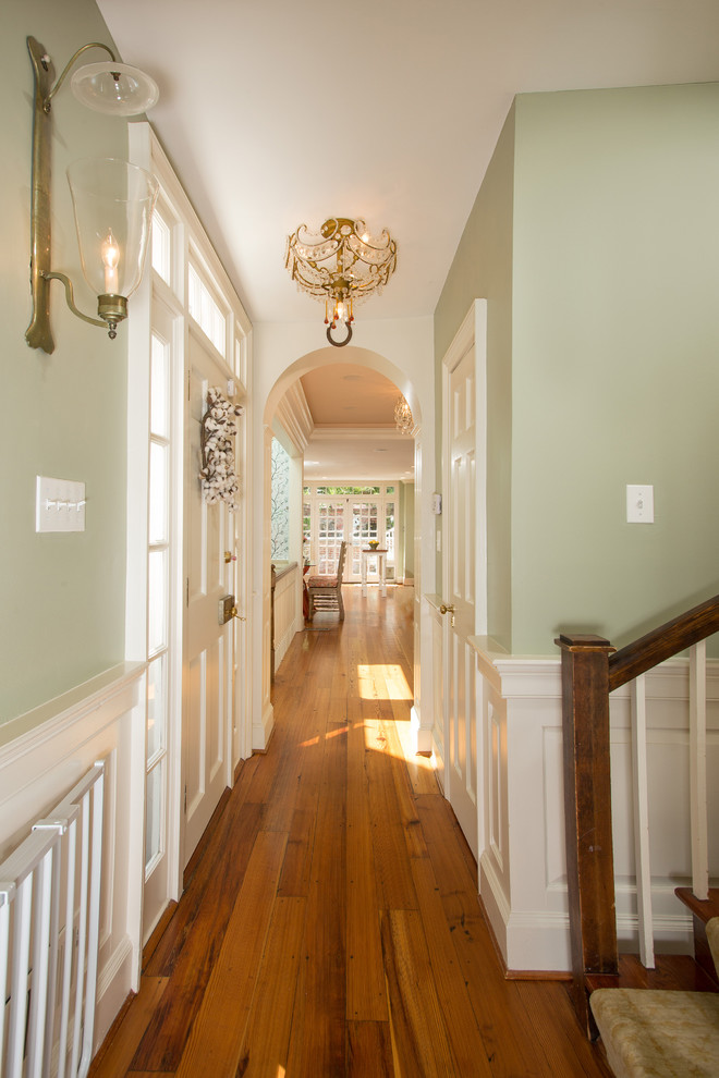 Cette photo montre un couloir chic avec un mur vert et un sol en bois brun.