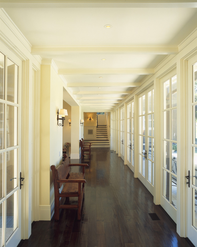 Cette photo montre un couloir chic avec un mur blanc, parquet foncé et un sol marron.