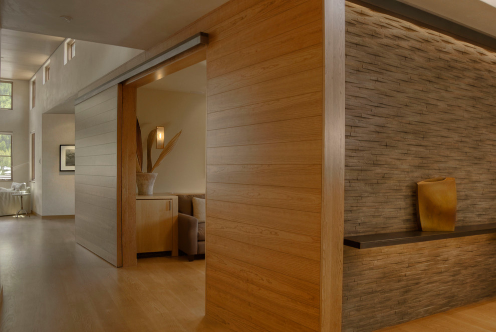 Cette photo montre un couloir tendance de taille moyenne avec un mur gris et un sol en bois brun.