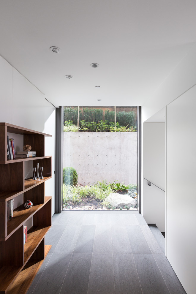 Inspiration pour un couloir minimaliste de taille moyenne avec un mur blanc et un sol gris.