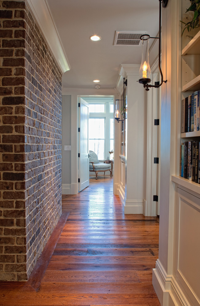 Example of a large classic medium tone wood floor hallway design in Charleston with white walls