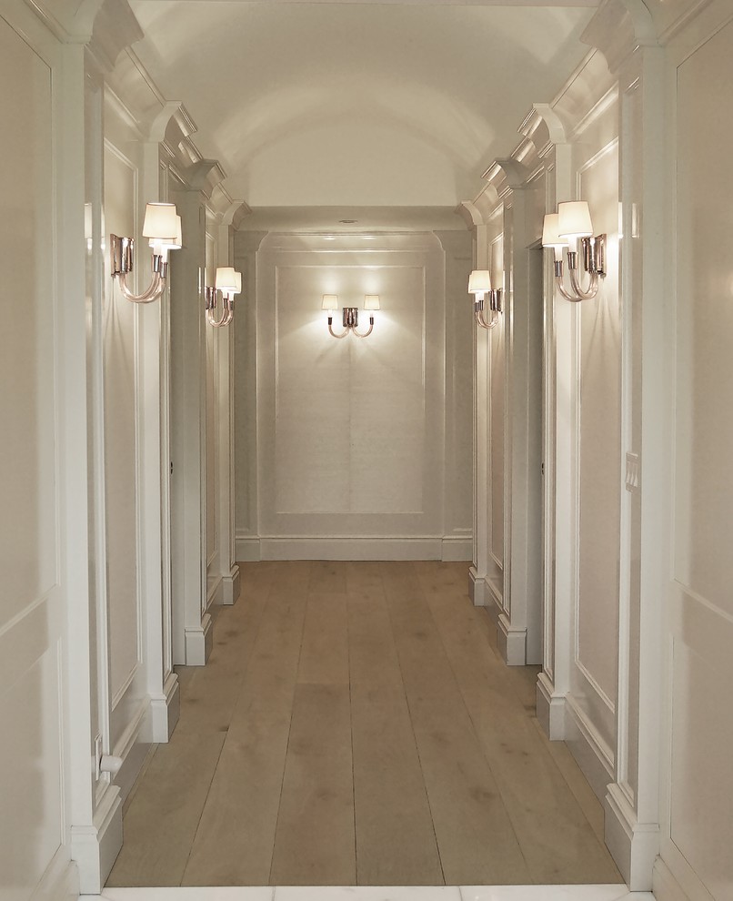 Cette image montre un couloir traditionnel en bois avec un mur blanc, parquet clair et un sol beige.