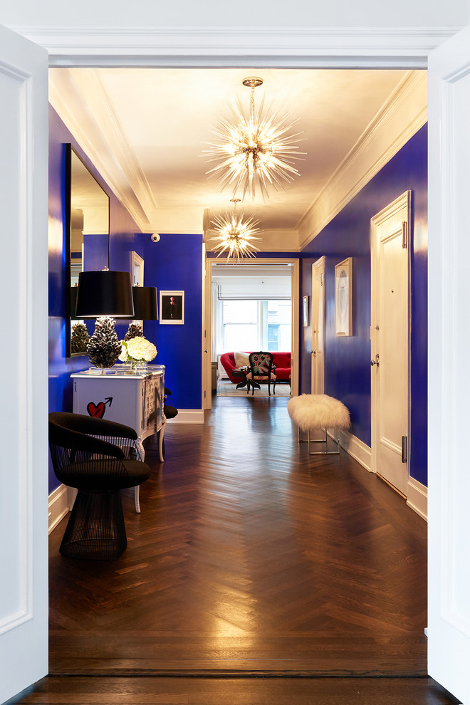 Exemple d'un grand couloir éclectique avec un mur bleu, parquet foncé et un sol marron.