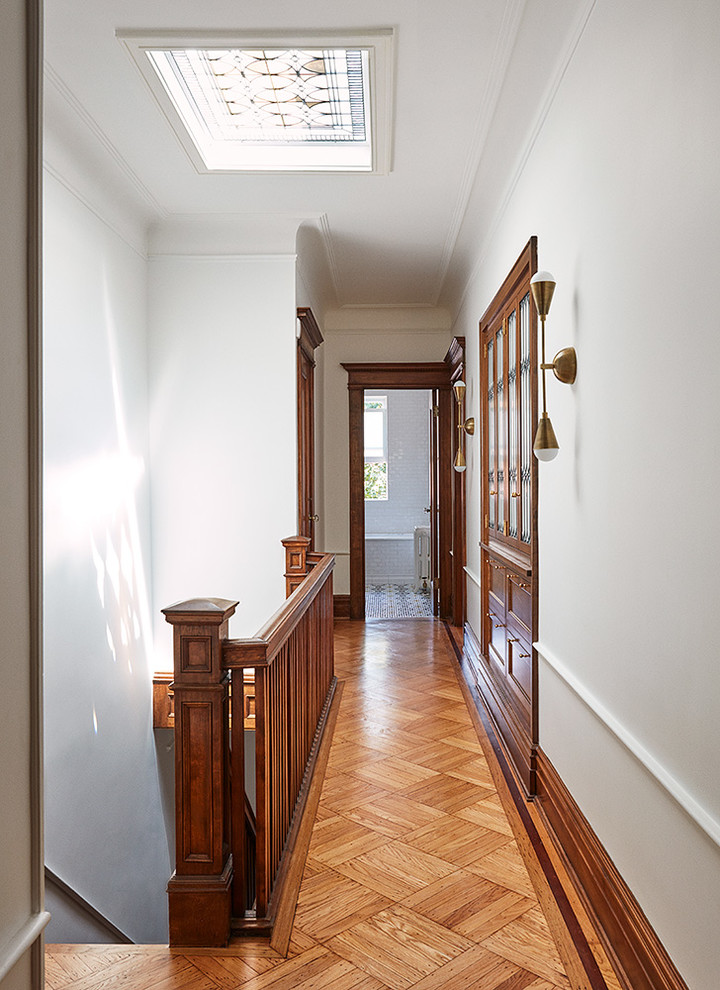 Idée de décoration pour un couloir tradition de taille moyenne avec un mur blanc et un sol en bois brun.