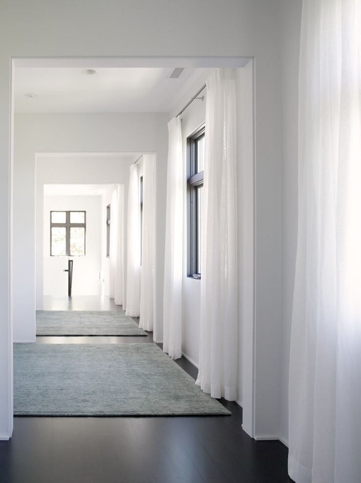Immagine di un grande ingresso o corridoio contemporaneo con pareti bianche e parquet scuro