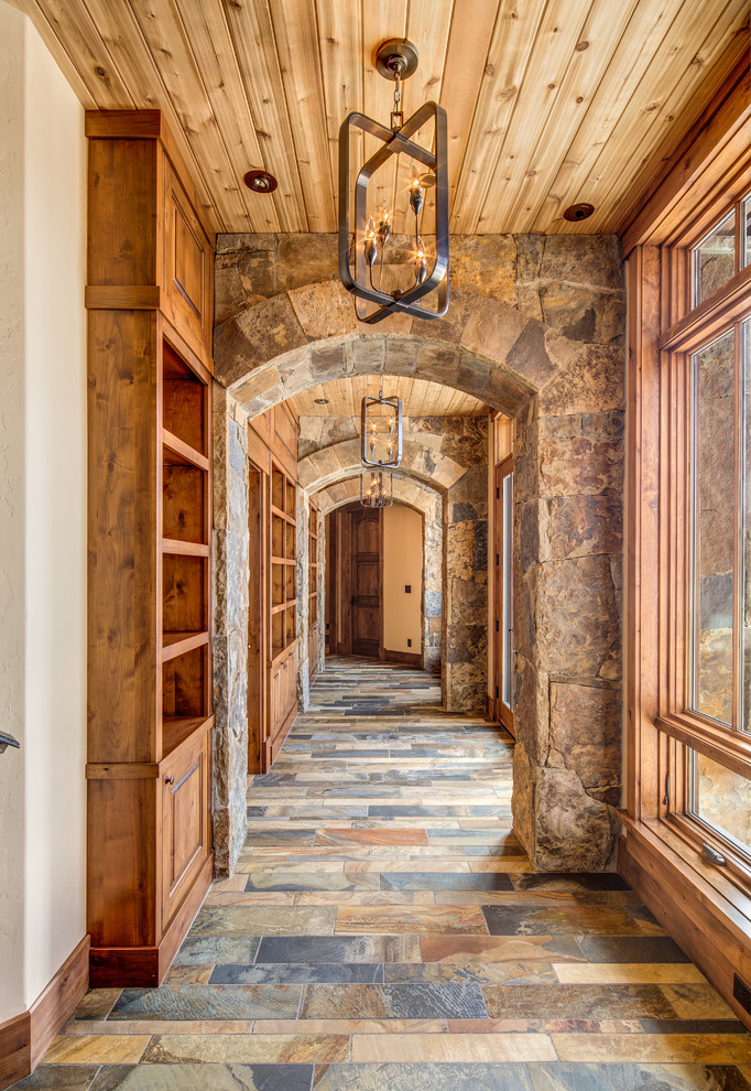 На фото: большой коридор в стиле рустика с коричневыми стенами и полом из сланца с
