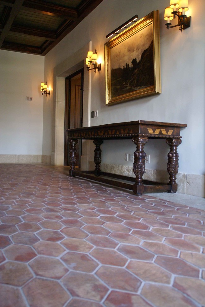 Exemple d'un couloir chic avec tomettes au sol.