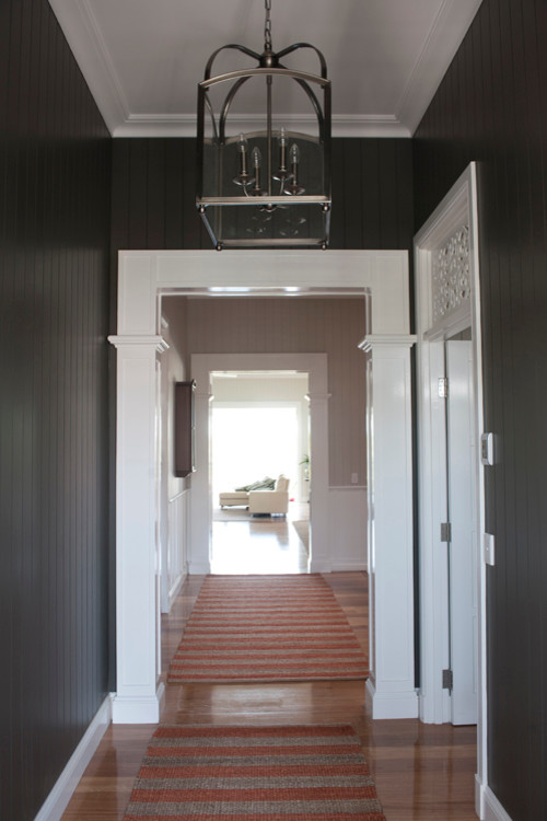 Inspiration pour un grand couloir traditionnel avec un mur noir et un sol en bois brun.