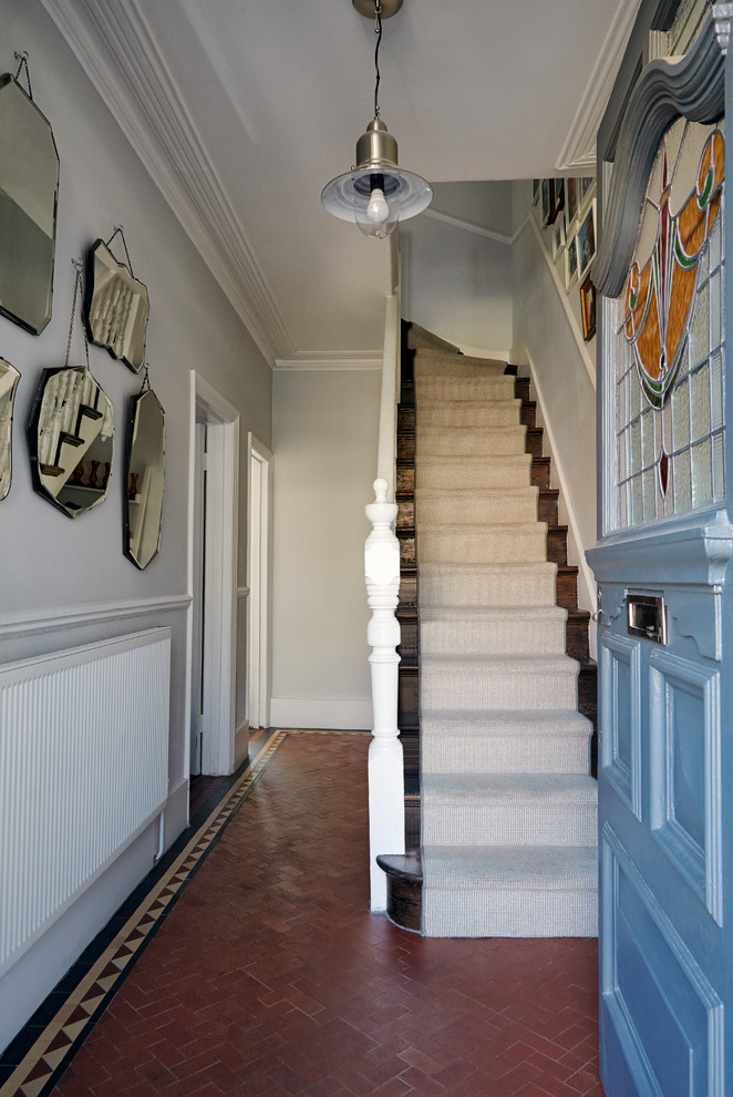 Cette image montre un petit couloir traditionnel avec un mur gris et tomettes au sol.
