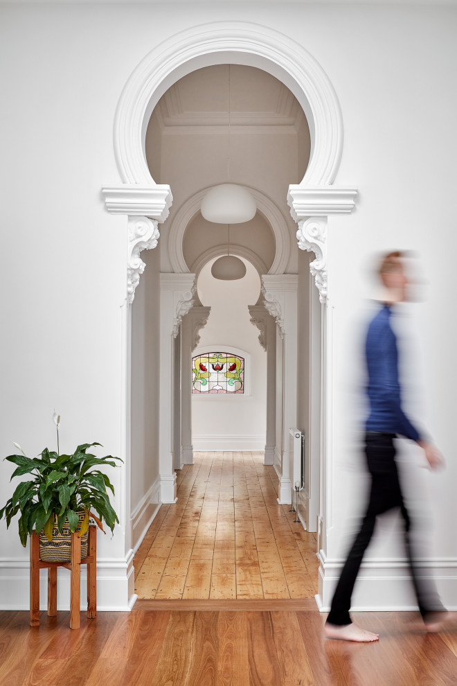 Foto di un ingresso o corridoio design con pareti bianche, pavimento in legno massello medio e pavimento marrone