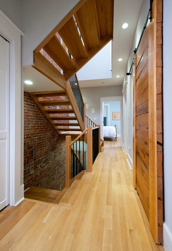 Inspiration for a mid-sized contemporary medium tone wood floor hallway remodel in Other with white walls