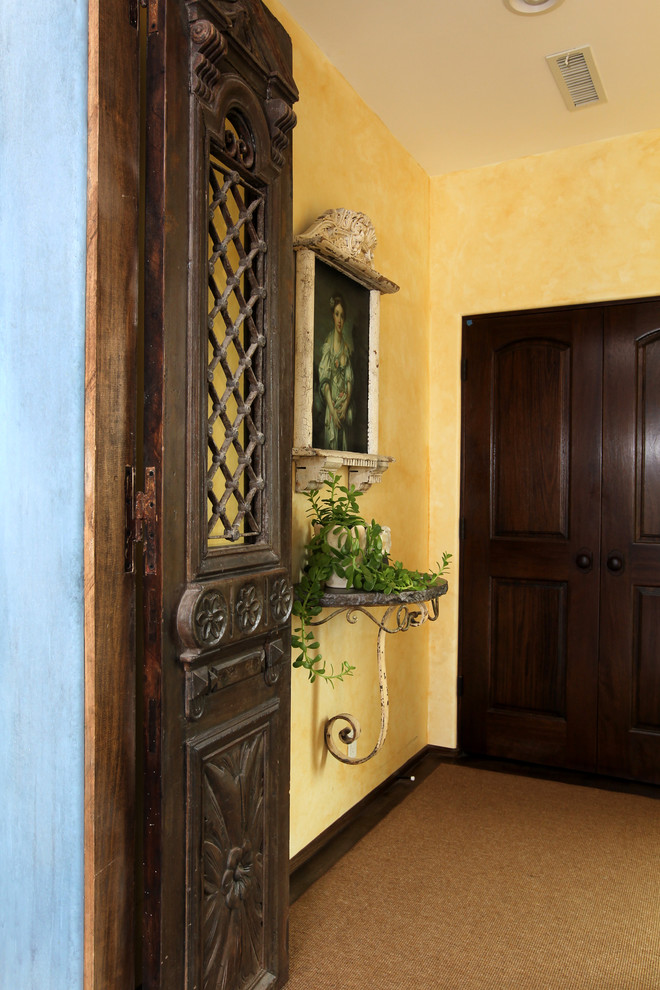 Immagine di un piccolo ingresso o corridoio mediterraneo con pareti gialle, moquette e pavimento marrone