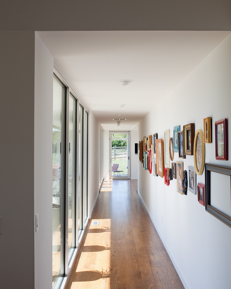 Example of a trendy medium tone wood floor hallway design in Kansas City with white walls