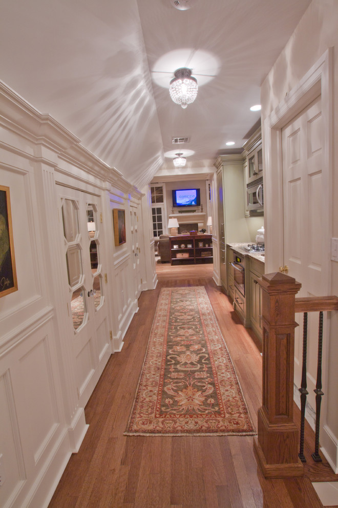 На фото: большой коридор в классическом стиле с белыми стенами и паркетным полом среднего тона с