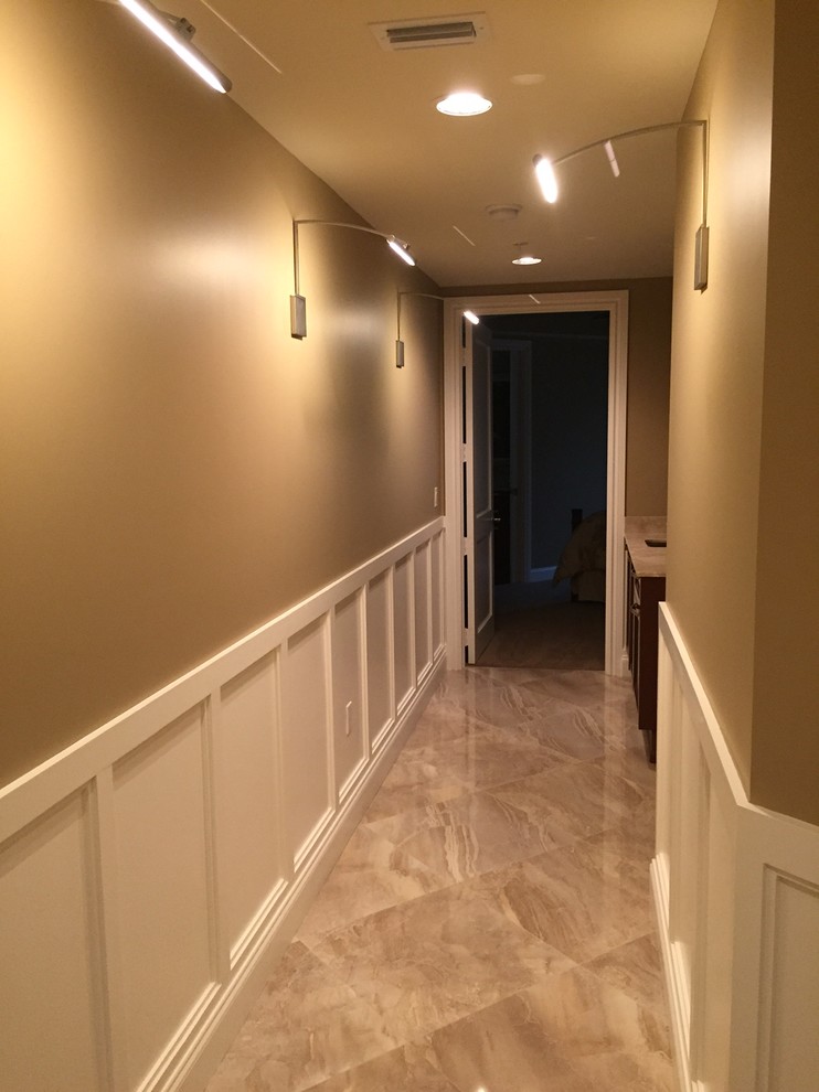 Inspiration pour un grand couloir design avec un mur beige et un sol en carrelage de porcelaine.