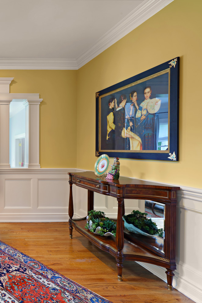 Стильный дизайн: коридор среднего размера в классическом стиле с желтыми стенами, паркетным полом среднего тона и коричневым полом - последний тренд