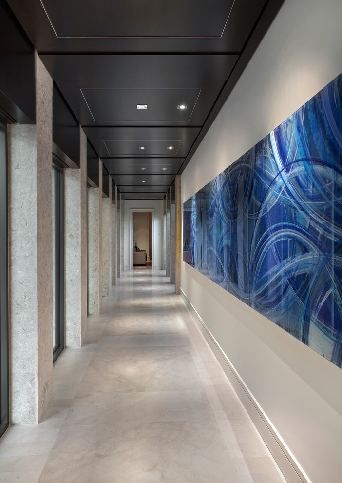На фото: огромный коридор в стиле неоклассика (современная классика) с белыми стенами и мраморным полом