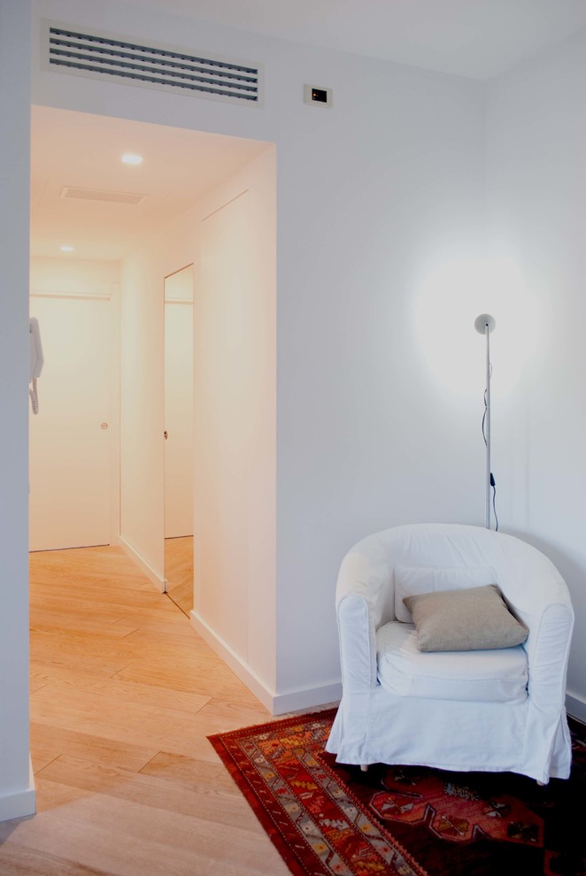 Example of a mid-sized minimalist light wood floor hallway design in Rome with white walls