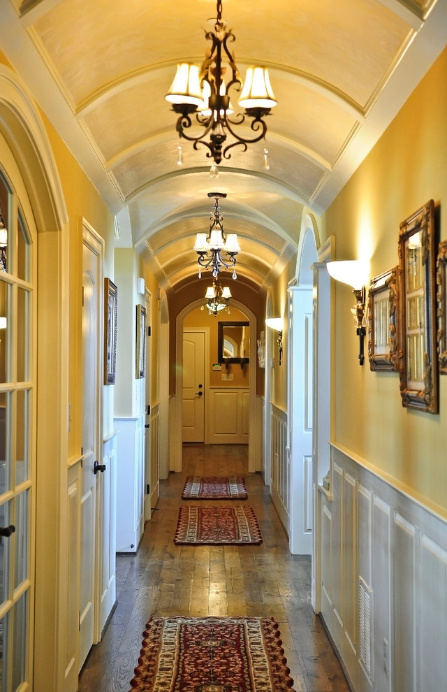 Diseño de recibidores y pasillos grandes con paredes amarillas, suelo de madera oscura y suelo marrón