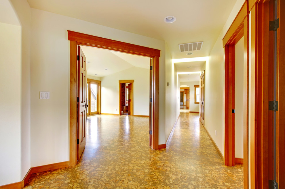 Cette image montre un grand couloir traditionnel avec un mur beige et un sol en liège.