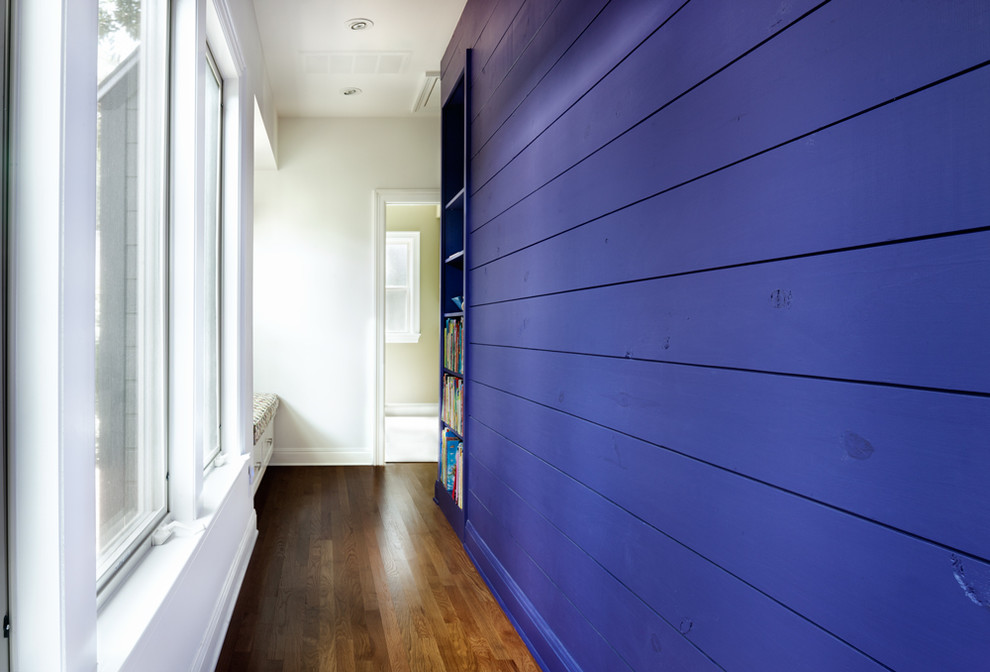 Cette photo montre un couloir tendance avec un mur violet et un sol en bois brun.