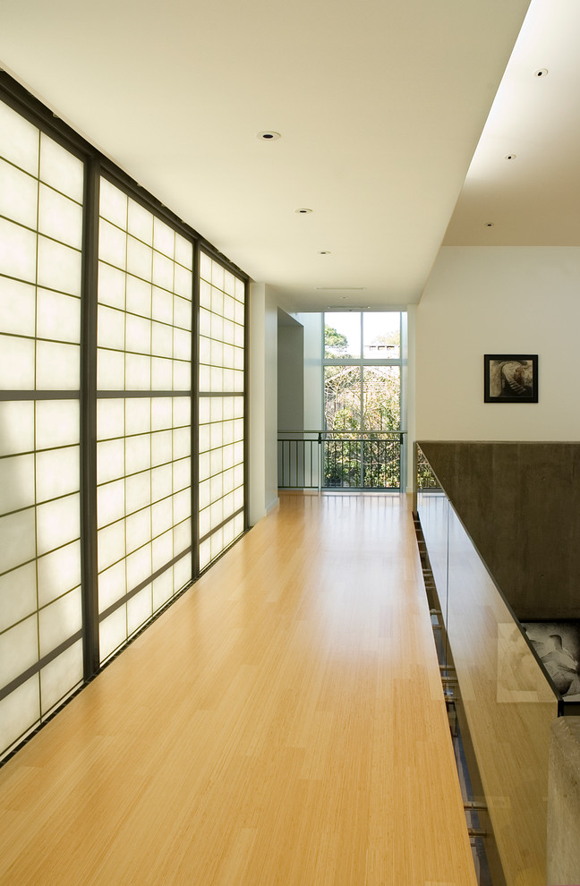 Idées déco pour un couloir moderne avec un mur blanc, parquet clair et un sol jaune.
