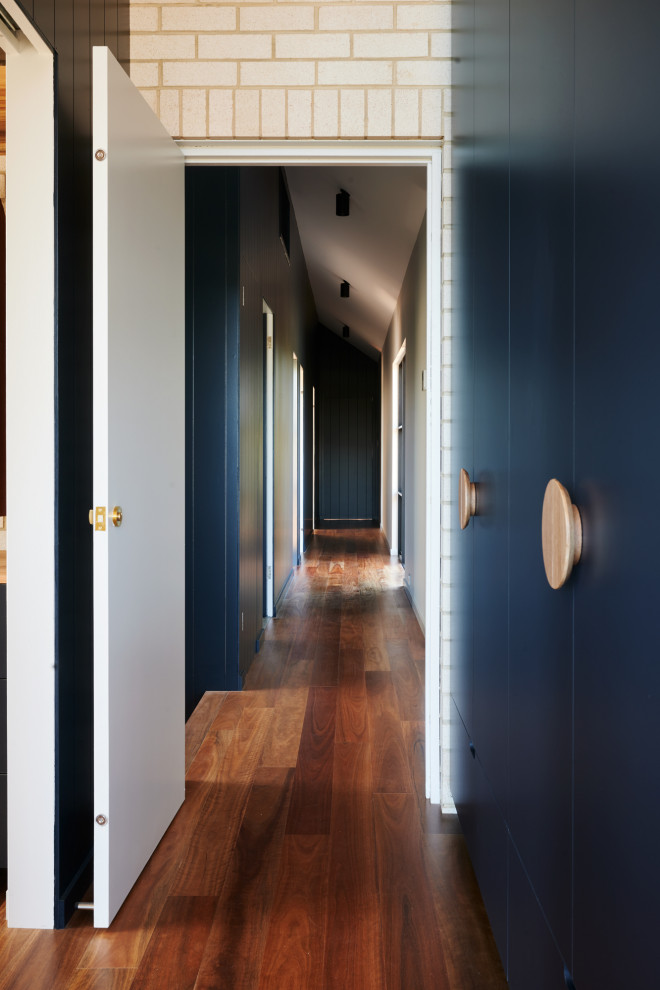 Cette photo montre un couloir avec un mur bleu, un sol en bois brun et un sol marron.