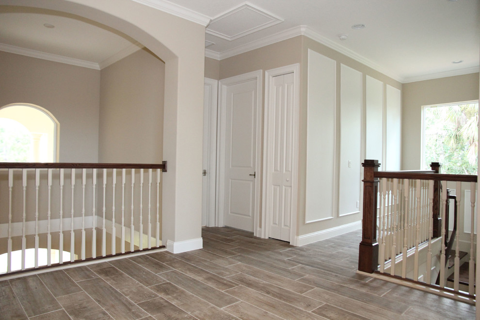 Cette image montre un couloir traditionnel de taille moyenne avec un mur beige, un sol en carrelage de céramique et un sol marron.