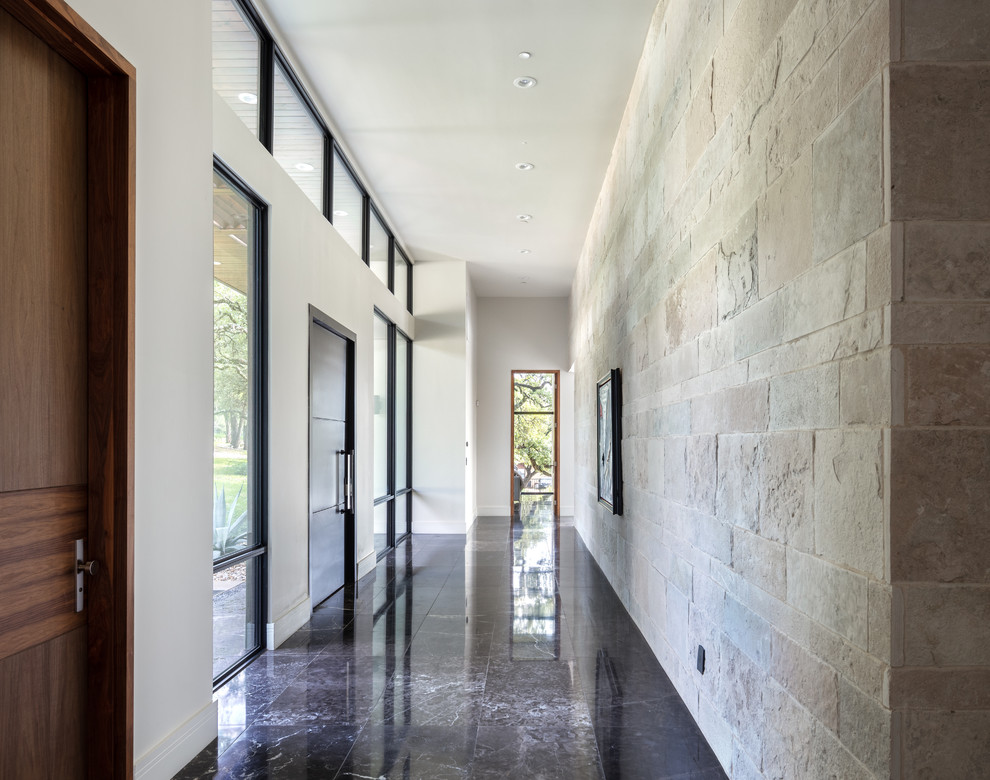 Réalisation d'un grand couloir design avec un sol en marbre et un sol noir.