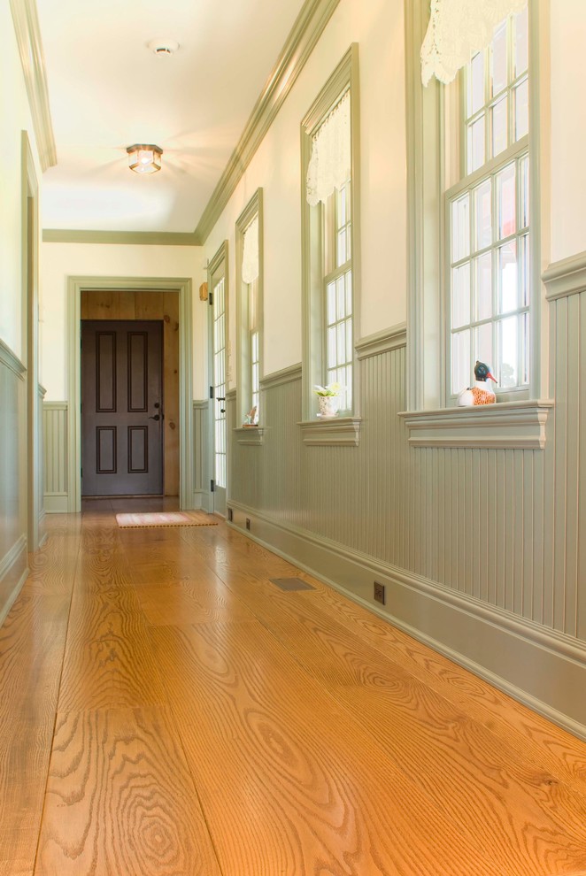 Idées déco pour un couloir classique avec un mur vert et un sol en bois brun.