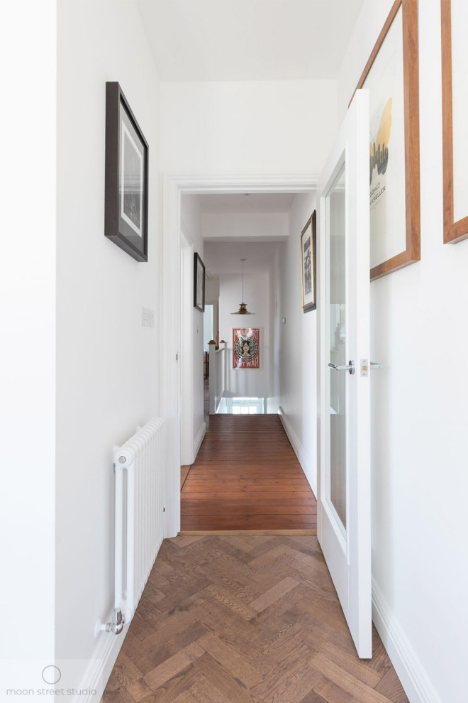 Esempio di un ingresso o corridoio design di medie dimensioni con pareti bianche, pavimento in legno massello medio e pavimento marrone