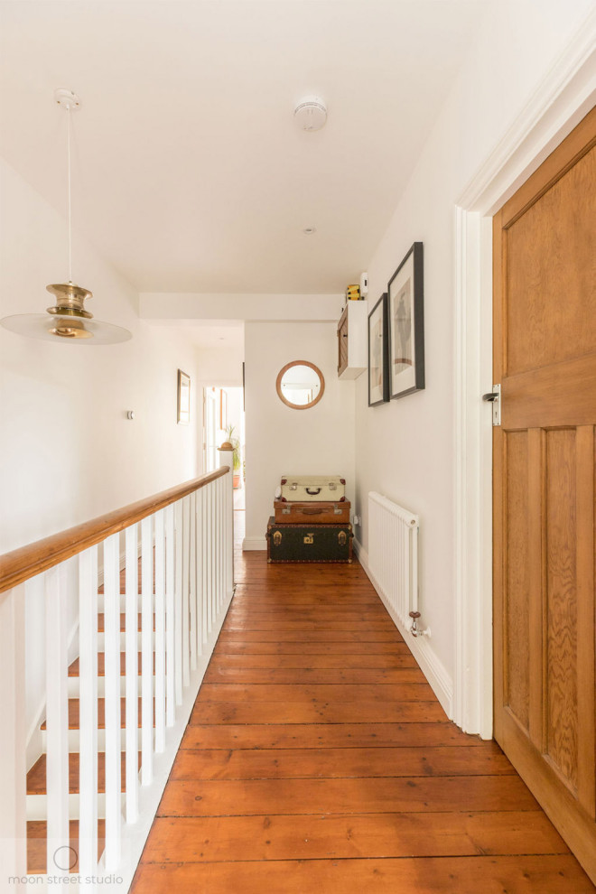 Foto di un ingresso o corridoio design di medie dimensioni con pareti bianche, pavimento in legno massello medio e pavimento marrone