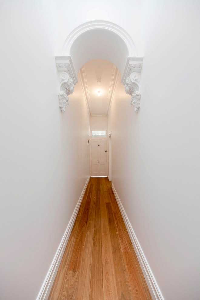 Immagine di un ingresso o corridoio tradizionale di medie dimensioni con pareti bianche, pavimento in legno massello medio e pavimento marrone