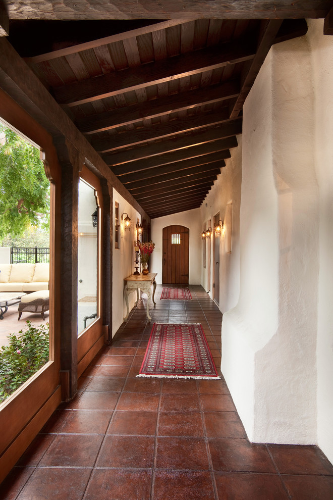 На фото: коридор в средиземноморском стиле с белыми стенами и полом из терракотовой плитки